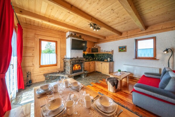 Una cabaña acogedora de madera con chimenea de piedra, mesa de comedor de madera y un sofá cómodo.