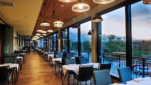 A restaurant with a long counter and tables, large windows with a view of the outdoors, and hanging pendant lights. - Hot Springs Medical and Spa Hotel (Razlog)