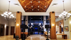 A lobby with a wooden ceiling, chandeliers, and a seating area with tables and chairs. - Hot Springs Medical and Spa Hotel (Razlog)