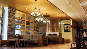 A cozy interior with wooden beams, a fireplace, and a seating area with a sofa and tables. - Hot Springs Medical and Spa Hotel (Razlog)