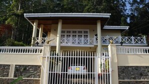 A two-story house with a gated entrance, a balcony, and a stone wall. - grymsby holiday bungalow (Nuwara Eliya)