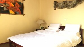 A neatly made bed with white linens in a room with a plain yellow wall. - grymsby holiday bungalow (Nuwara Eliya)