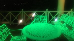 A green-lit outdoor seating area with a table and chairs, a white railing, and a view of the night sky. - grymsby holiday bungalow (Nuwara Eliya)