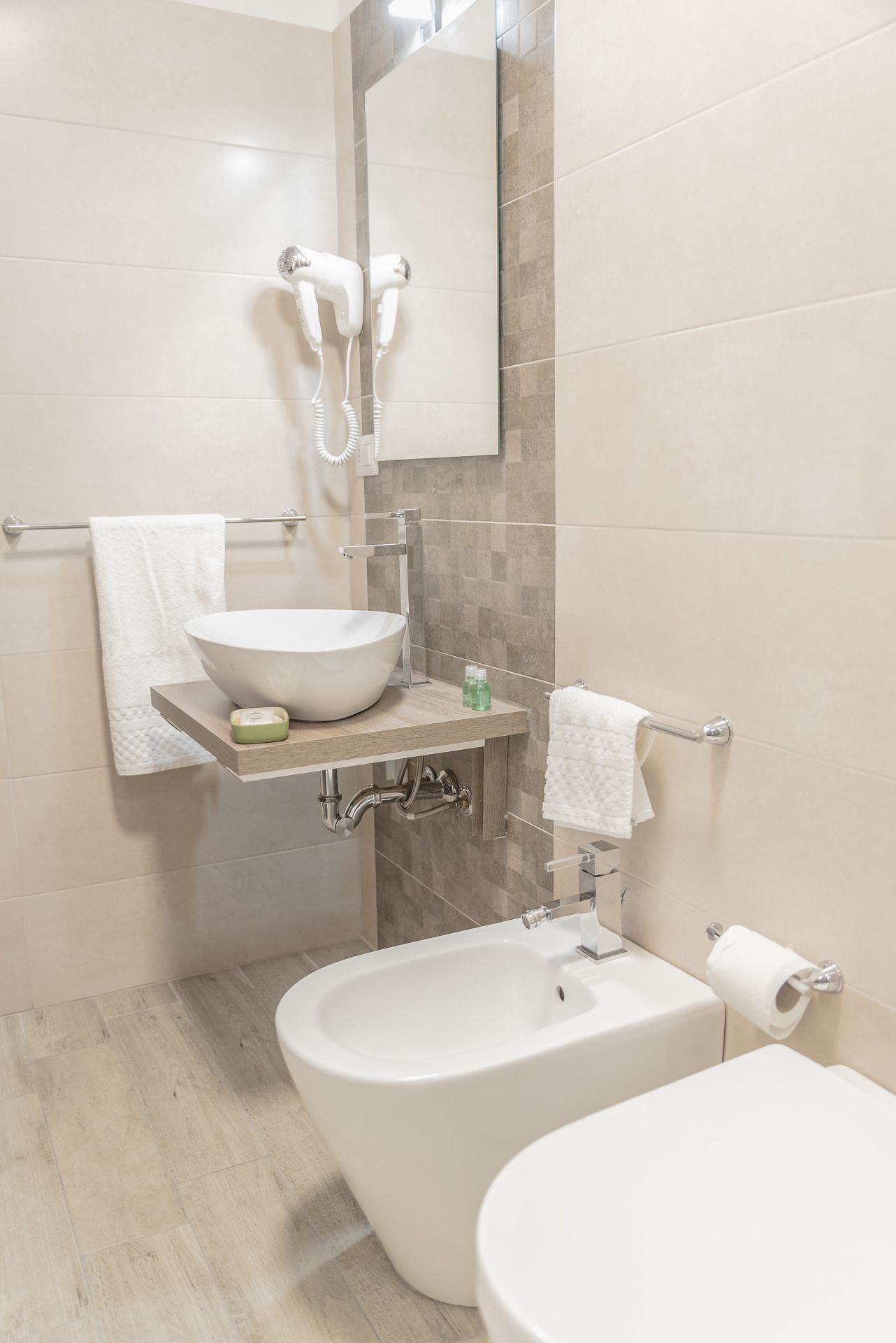 Ein modernes Badezimmer mit freistehender Badewanne, einem Waschbecken mit integriertem Becken, einer Toilette und einem Handtuchhalter.