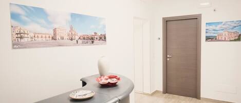 A hotel lobby with a reception desk, a large framed picture of a building, and a door.