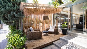 An outdoor seating area with wicker furniture, a small table, and a potted plant. - Mikelina Boutique Hotel (Pallini)
