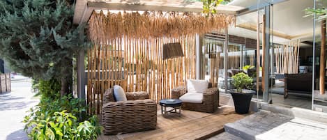 An outdoor seating area with wicker furniture, a small table, and a potted plant.