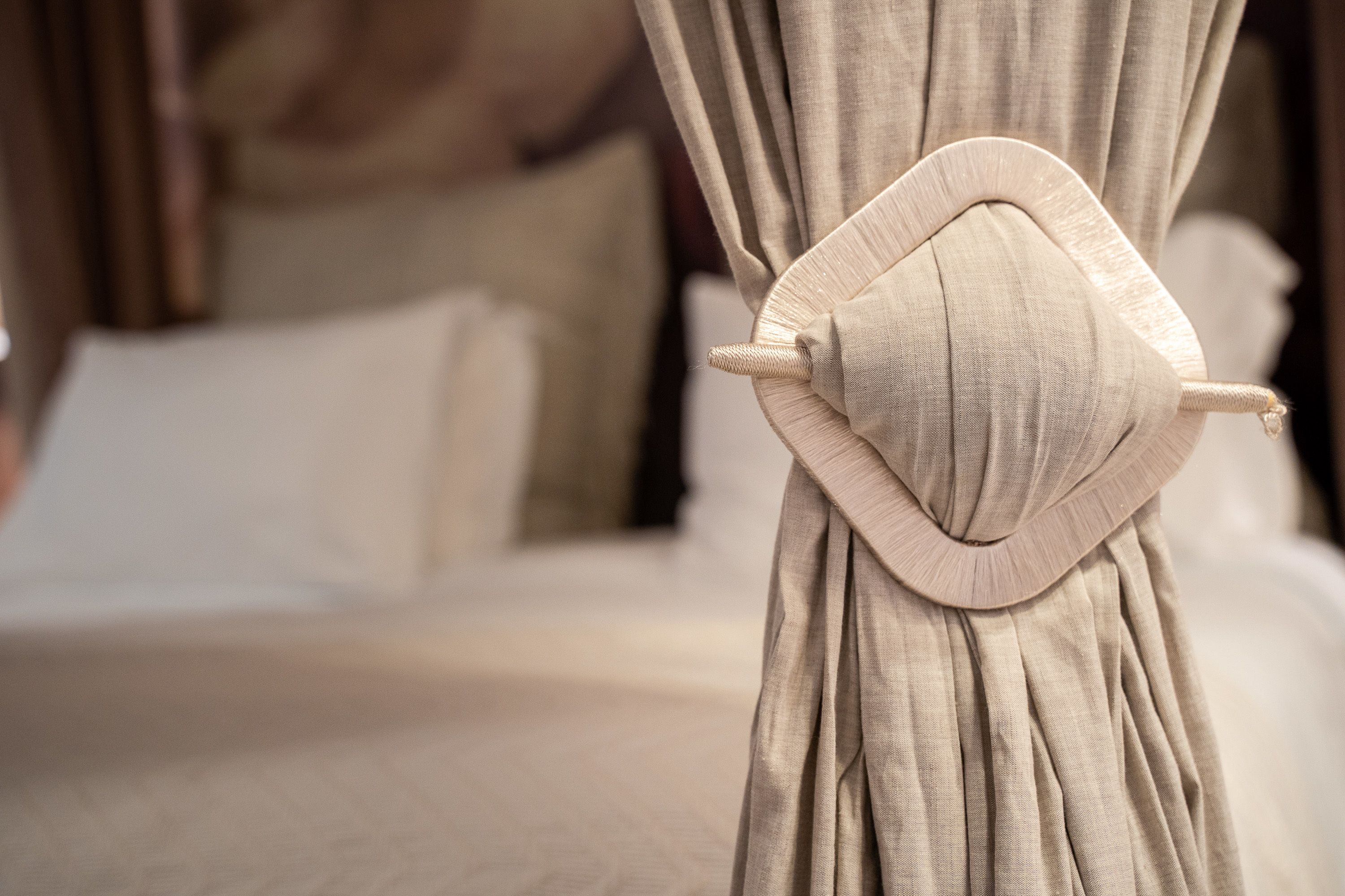 Una cama con cabecera, cortina y almohada.