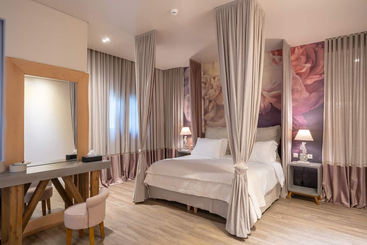 Un dormitorio con cama con dosel, un escritorio con silla y una mesita de noche con lámpara.