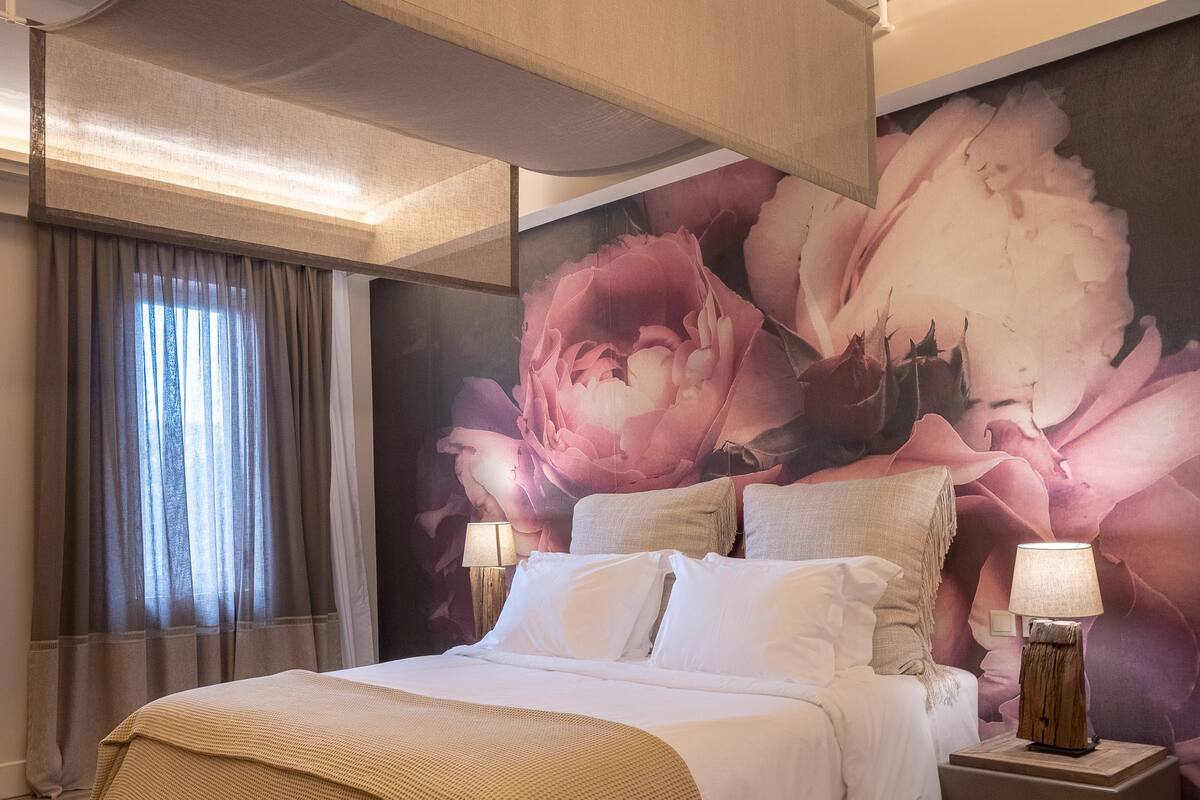 Un dormitorio espacioso con una cama grande, dosel y un mural floral en la pared.