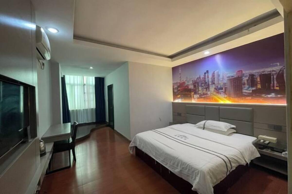 Een hotelkamer met een bed, een bureau en een groot stadsmuur op de muur.