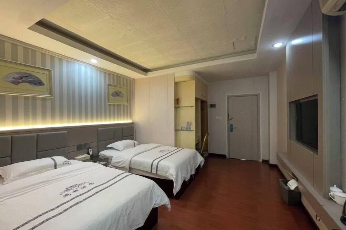 Een hotelkamer met twee bedden, een televisie en een badkamer die door een open deur zichtbaar is.