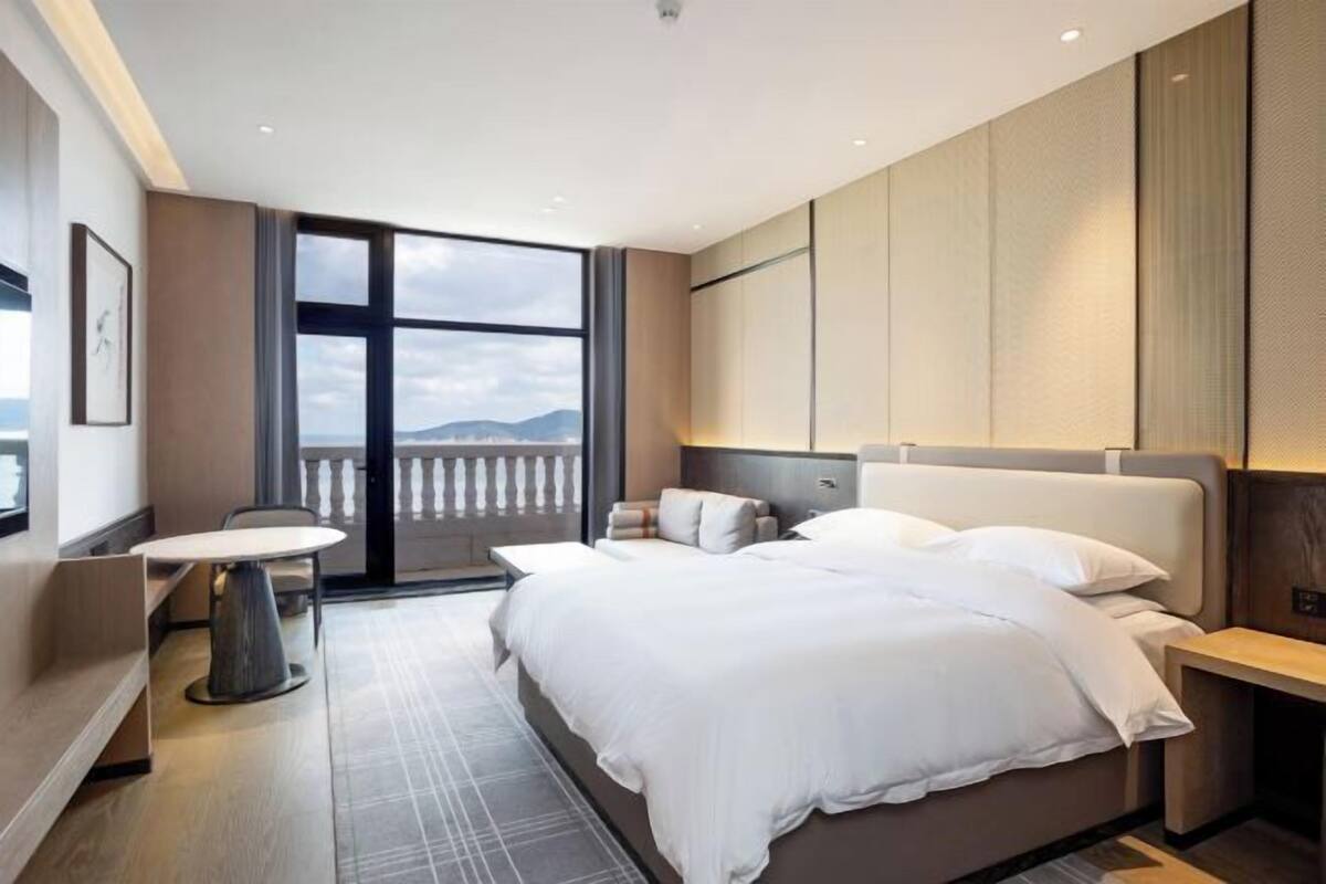 Une chambre d’hôtel moderne avec un grand lit, une petite table et un balcon offrant une vue agréable.