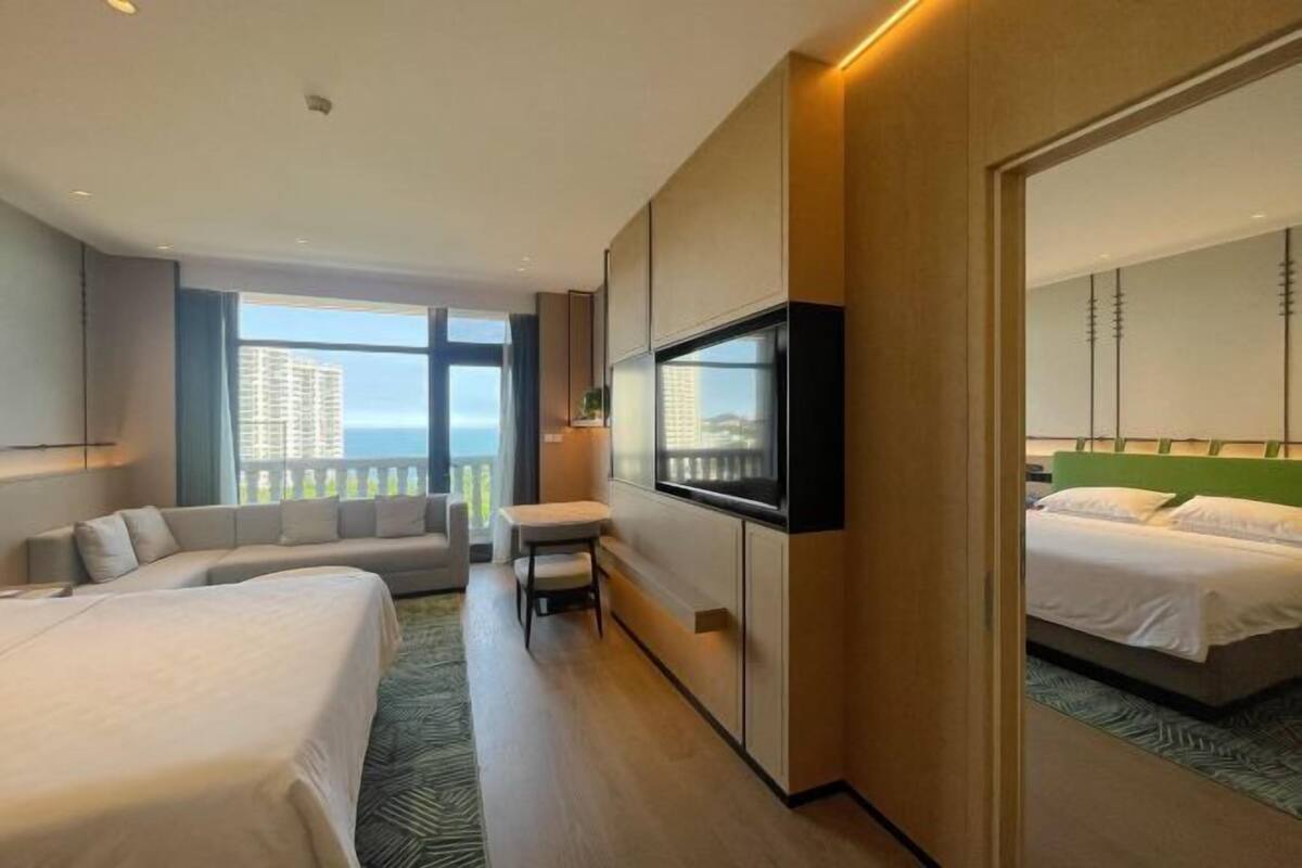 Une chambre d’hôtel avec un lit, un canapé, une télévision et un balcon offrant une vue sur la ville.