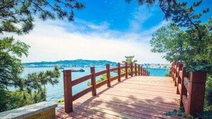 A wooden deck with a red railing overlooking a body of water and distant cityscape. - Weihai Dongshan Hotel (Weihai)