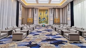 A conference room with a long table and rows of chairs, a large abstract painting on the back wall, and a patterned carpet. - Weihai Dongshan Hotel (Weihai)