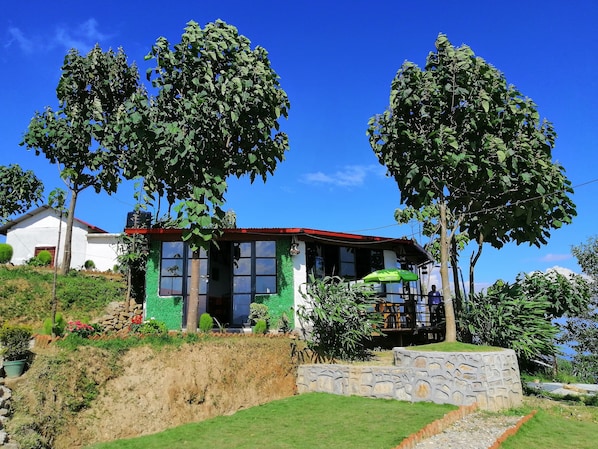 Set amidst lush greenery, this two-story house offers a serene retreat with a garden and a stone wall border.