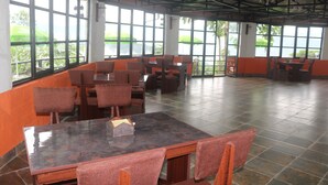 A spacious indoor area with large windows, multiple seating arrangements, and a tiled floor. - OP Village Resort (Ravi Opi)
