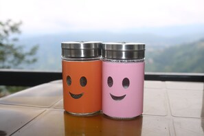 Two stainless steel containers with smiley face designs sit on a table, offering a view of the surrounding mountains.