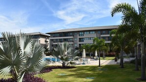 A hotel courtyard with a swimming pool, palm trees, and a multi-story building with balconies. - Eco Life Porto De Galinhas (Ipojuca)