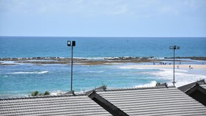 A coastal view with a beach, rocky shoreline, and two street lamps. - Eco Life Porto De Galinhas (Ipojuca)