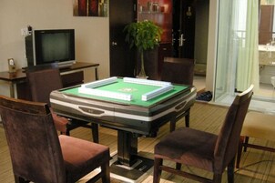 Una mesa de billar con sillas alrededor, un televisor y una planta en la habitación.