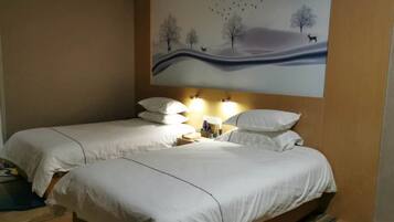 Habitación de hotel con dos camas, una mesita de noche con lámparas y un mural en la pared con un paisaje.