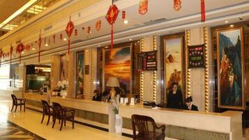 A hotel reception area with a long counter, chairs, and decorative lanterns.