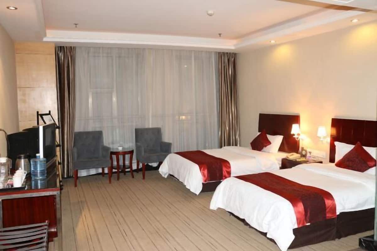 Une chambre d’hôtel avec deux lits, une télévision, un bureau et une chaise.