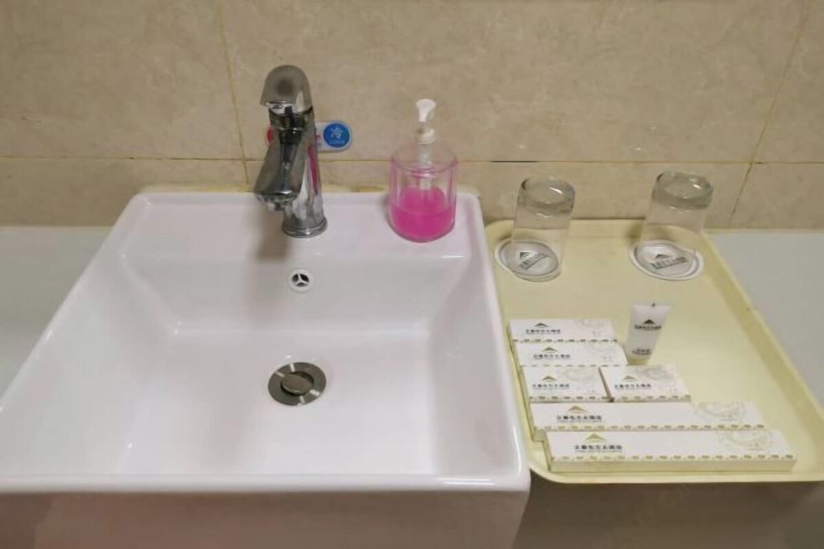 Un lavabo de salle de bain avec un robinet, un distributeur de savon et des articles de toilette.