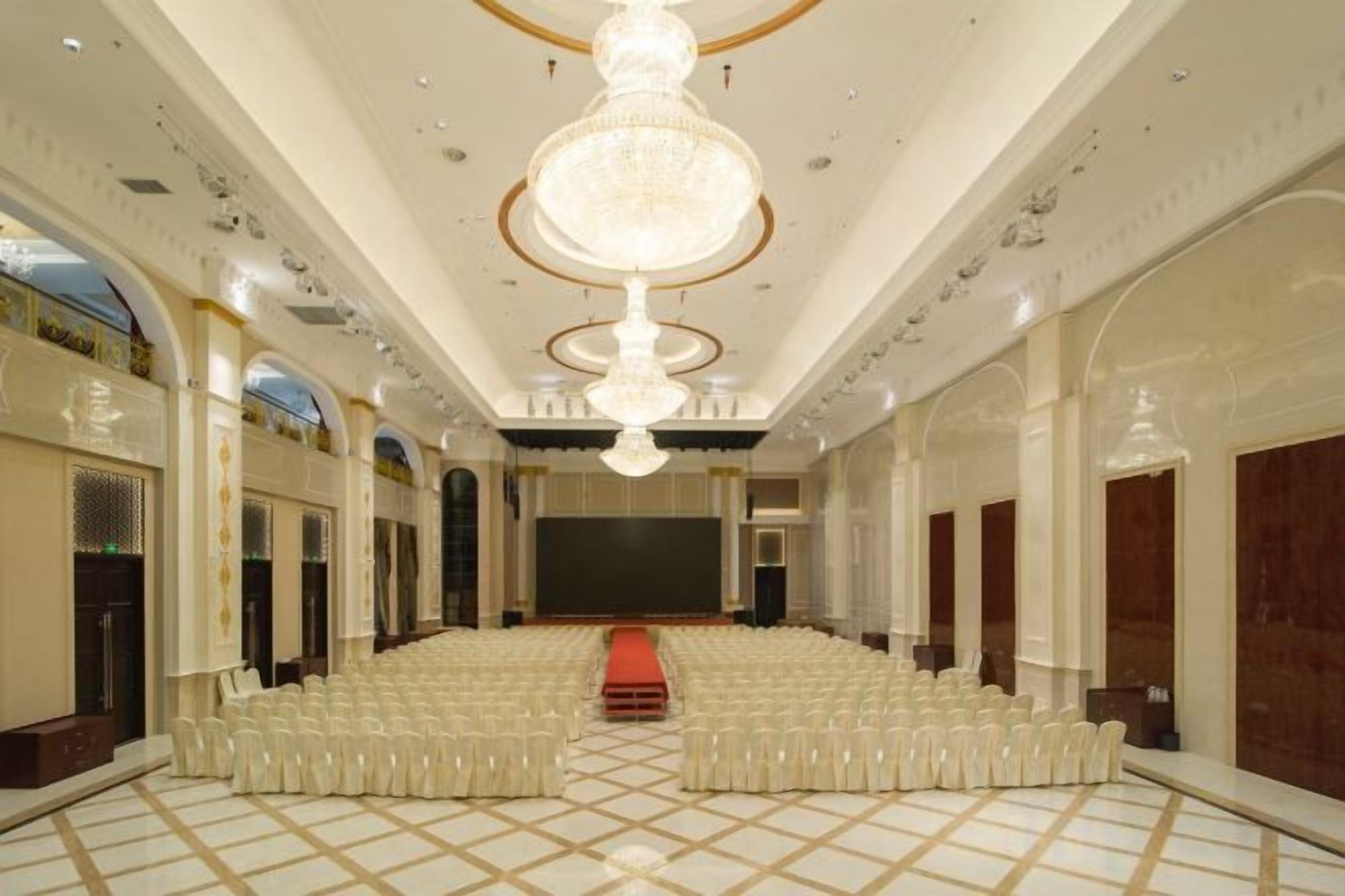 A large hall with tiered seating, a central stage, and a chandelier.