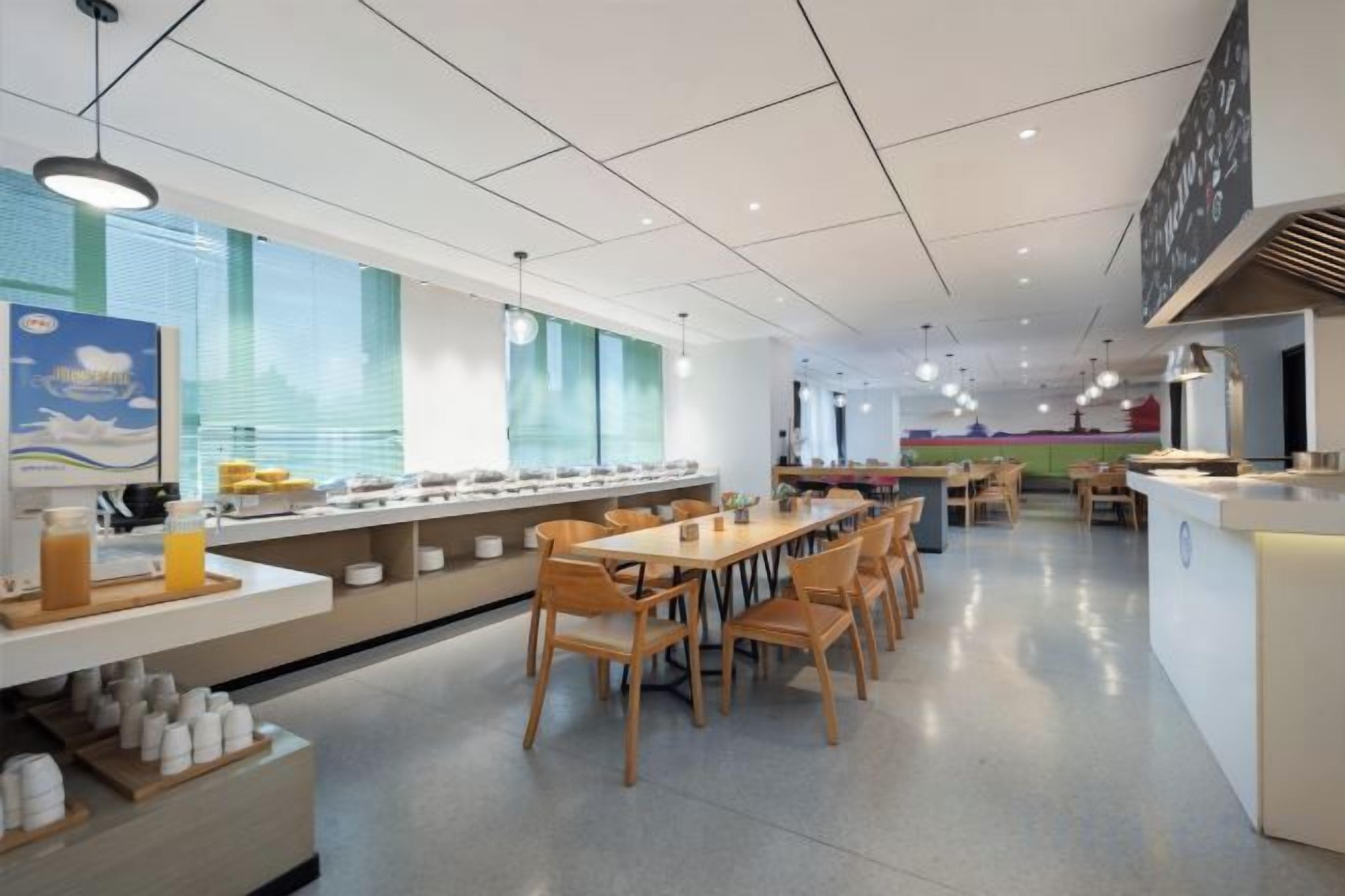 Una cafetería amplia con mesas y sillas largas, una zona de bufé y un mostrador con un menú.