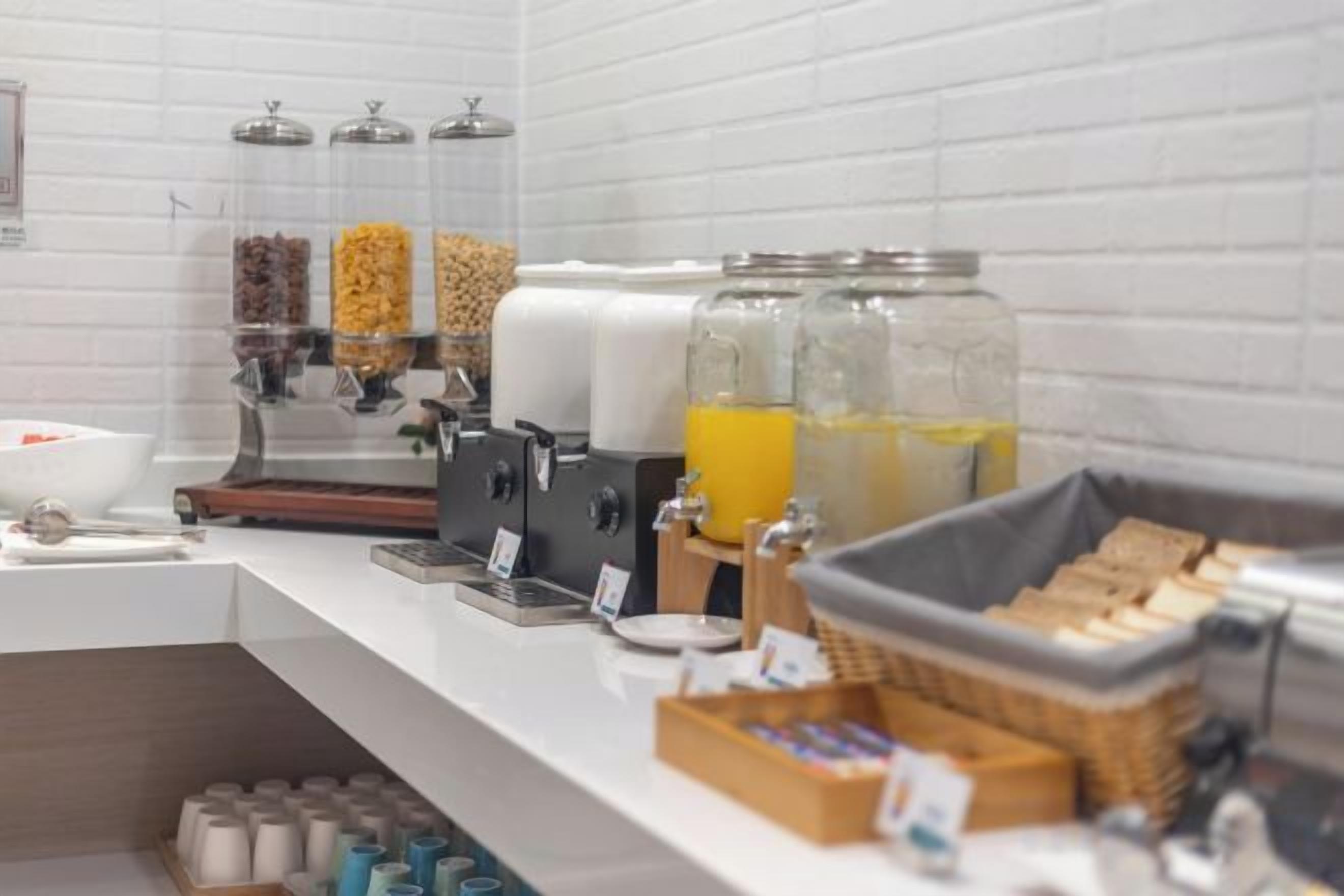 Een ontbijtbalk met een koffieapparaat, sapautomaten en diverse etenswaren.