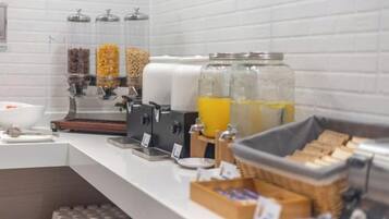 Een ontbijtbalk met een koffieapparaat, sapautomaten en diverse etenswaren.