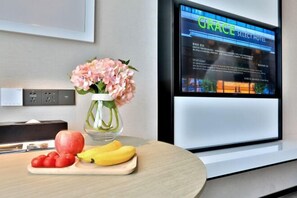 Enjoy a comfortable stay in this stylish room featuring a flat-screen TV, a small dining area with a vase, and a convenient workspace.