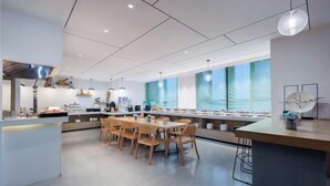 Una cucina moderna con isola centrale, sedie in legno e un lungo tavolo da pranzo.