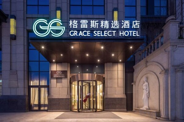 The exterior of the GRACE SELECT HOTEL with a prominent entrance, a revolving door, and classical architectural elements.