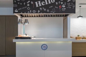 A modern kitchen with a white countertop, a black backsplash with doodles, and a blue circular logo.