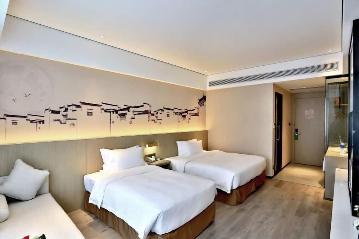 A hotel room with two beds, a wall-mounted artwork, and a modern design.