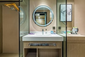 A modern bathroom with a large mirror, a white sink, and a wooden cabinet.