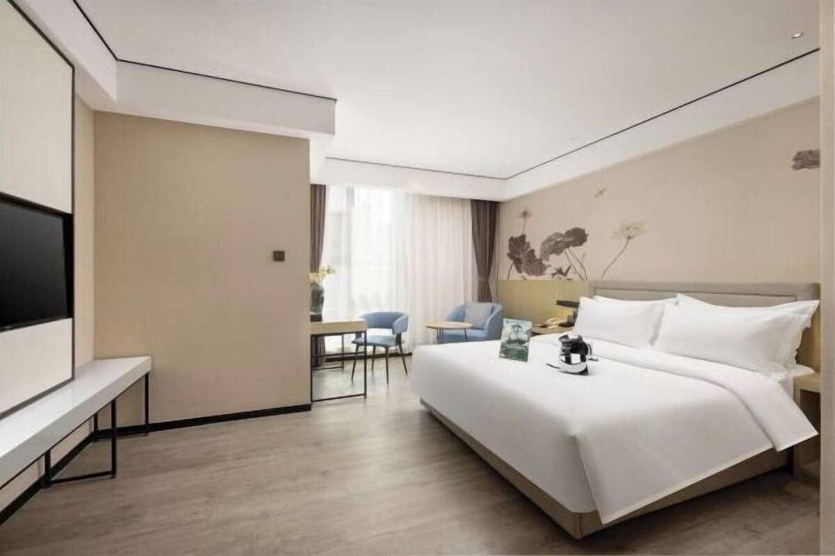 A hotel room with a bed, a TV, a desk, and a chair.