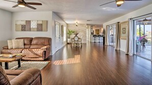 A spacious living room with a leather sofa, a dining table, and a ceiling fan. - Marco Island Home w/ Pool Near Tigertail Beach! (Marco Island)
