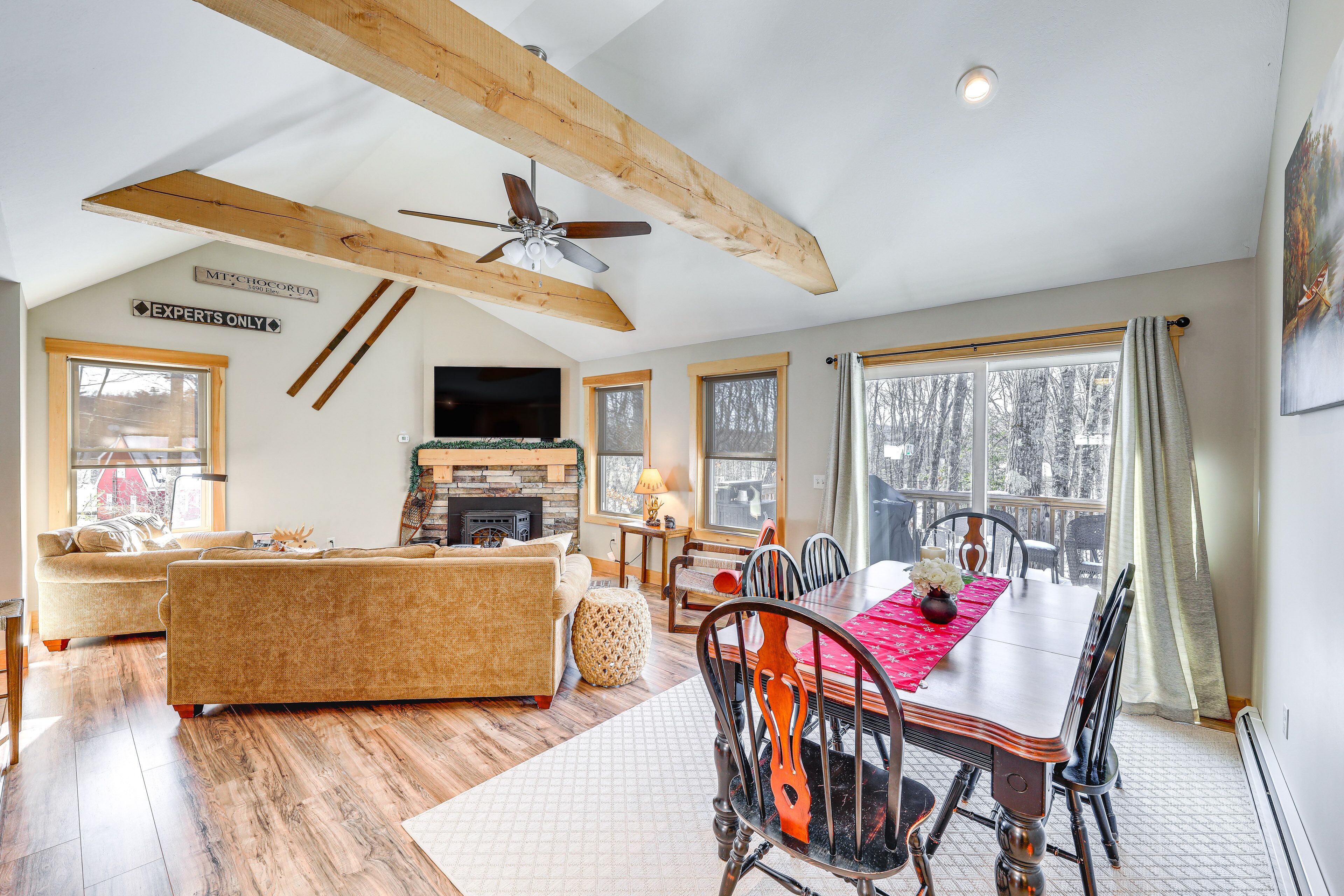 A spacious living area with a fireplace, a dining table, and a large window.