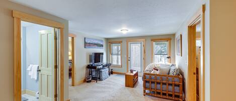 A spacious living room with a large window, a television, and a comfortable seating area.