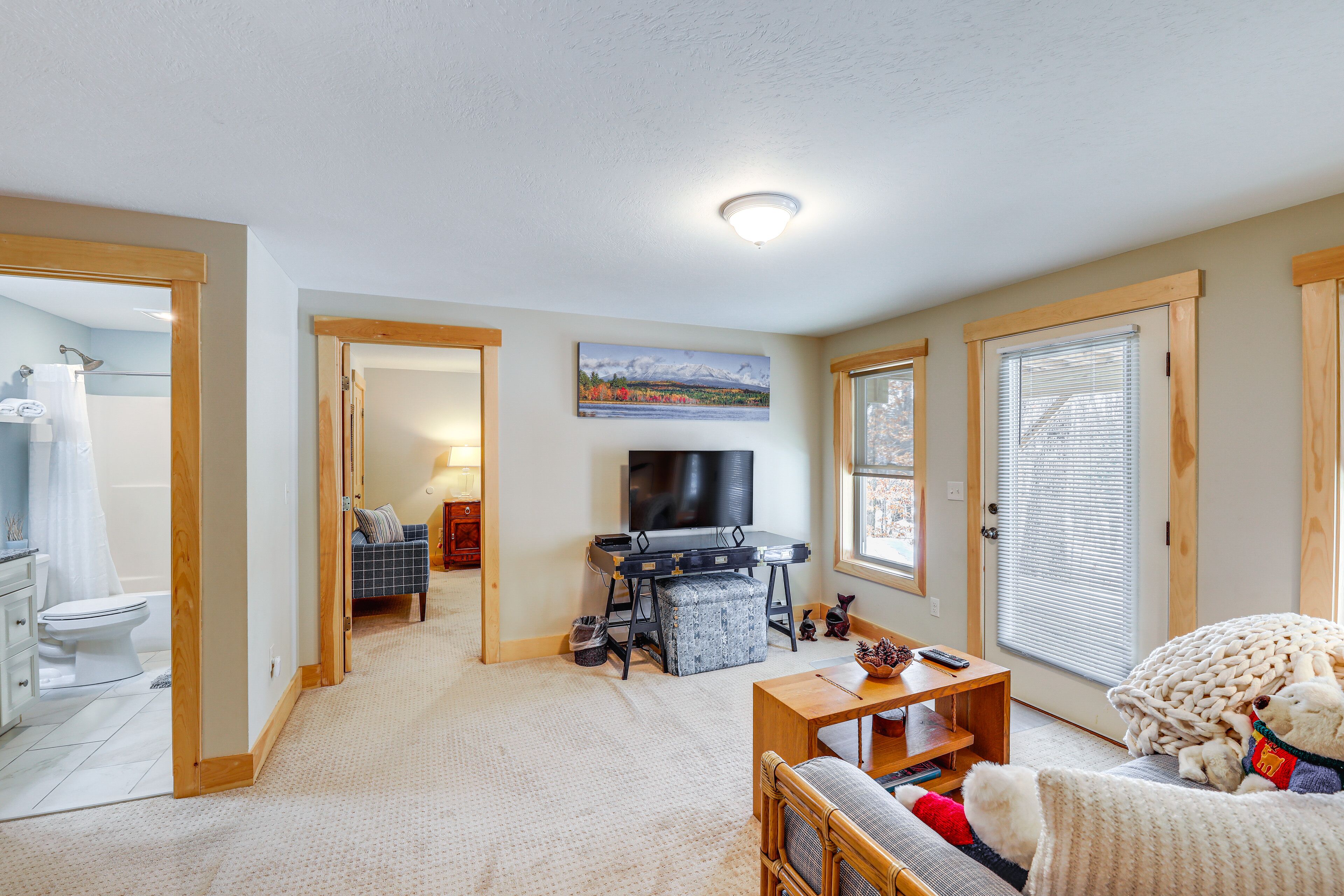 A living room with a TV, a sofa, a coffee table, and a window with blinds.