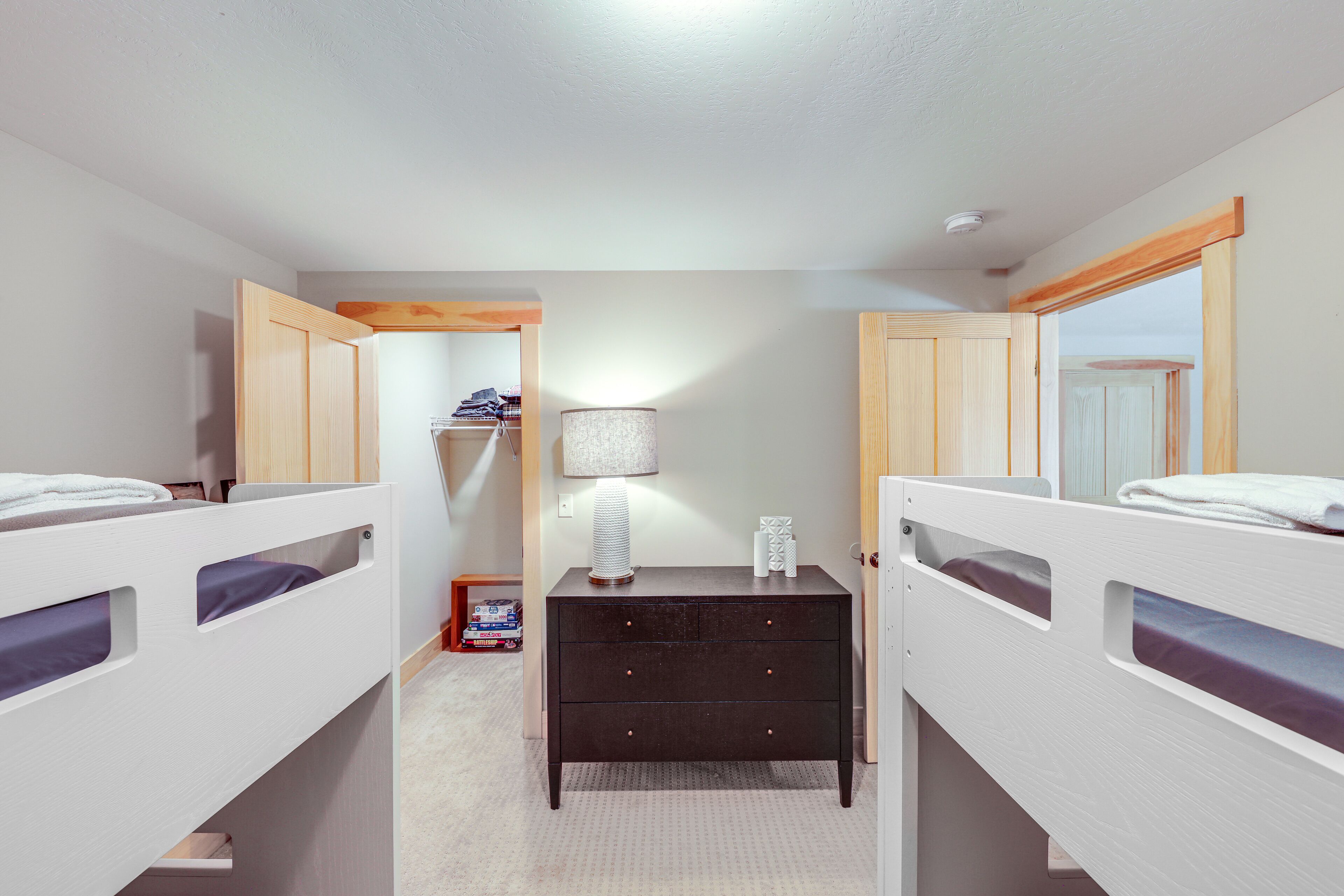 Een slaapkamer met stapelbedden, een dressoir, een lamp en een kast.