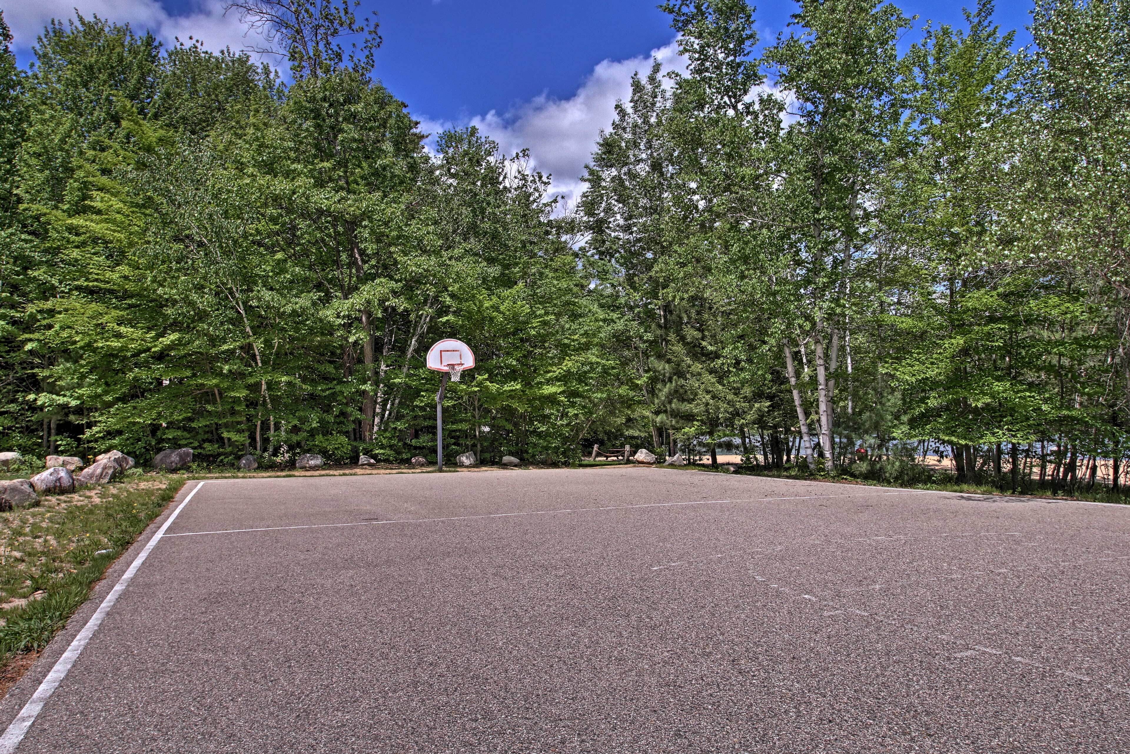 An outdoor basketball court surrounded by trees.