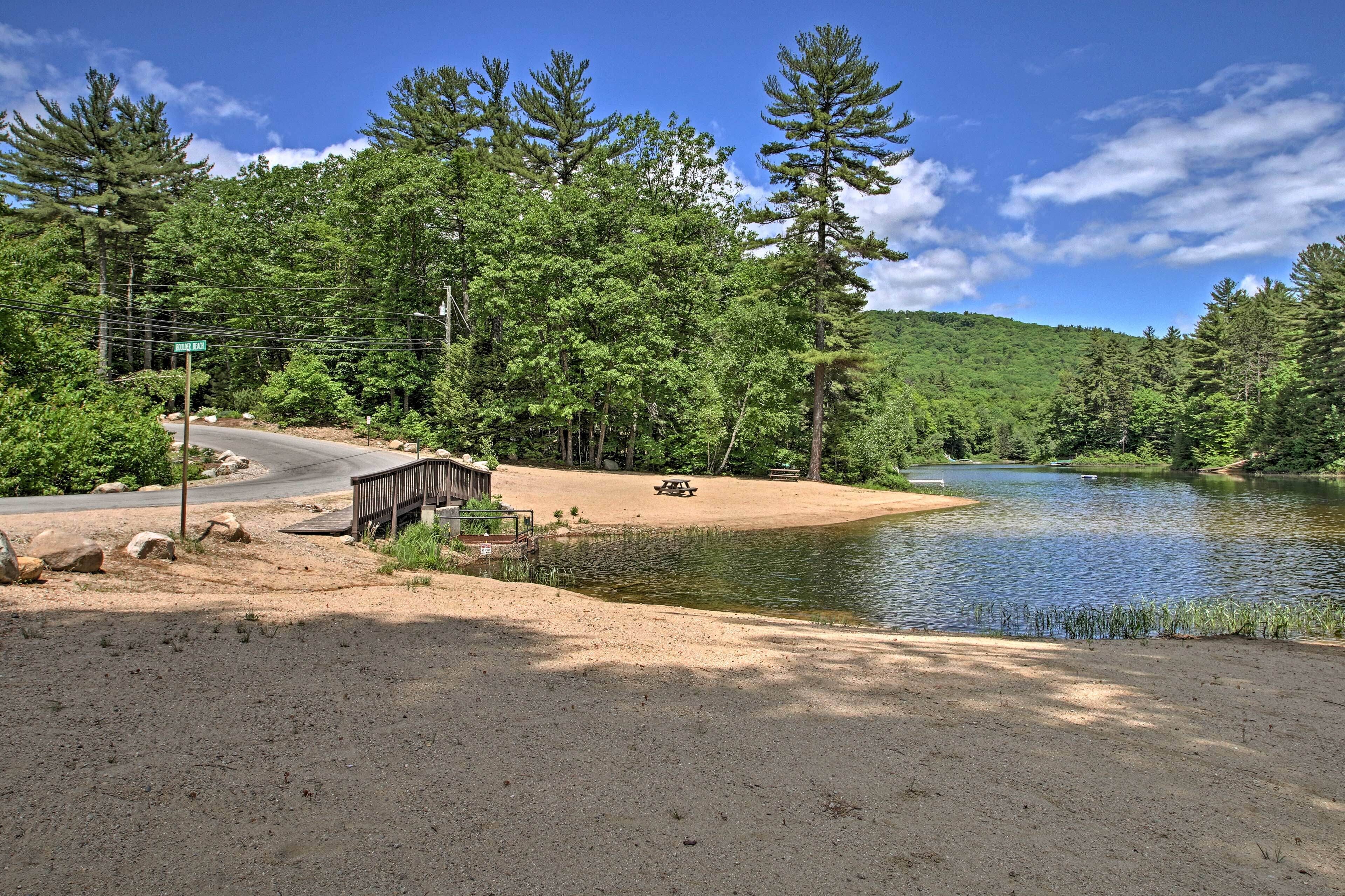 Un terrain de camping équipé d’une table de pique-nique, d’un pont en bois et d’un lac entouré d’arbres.