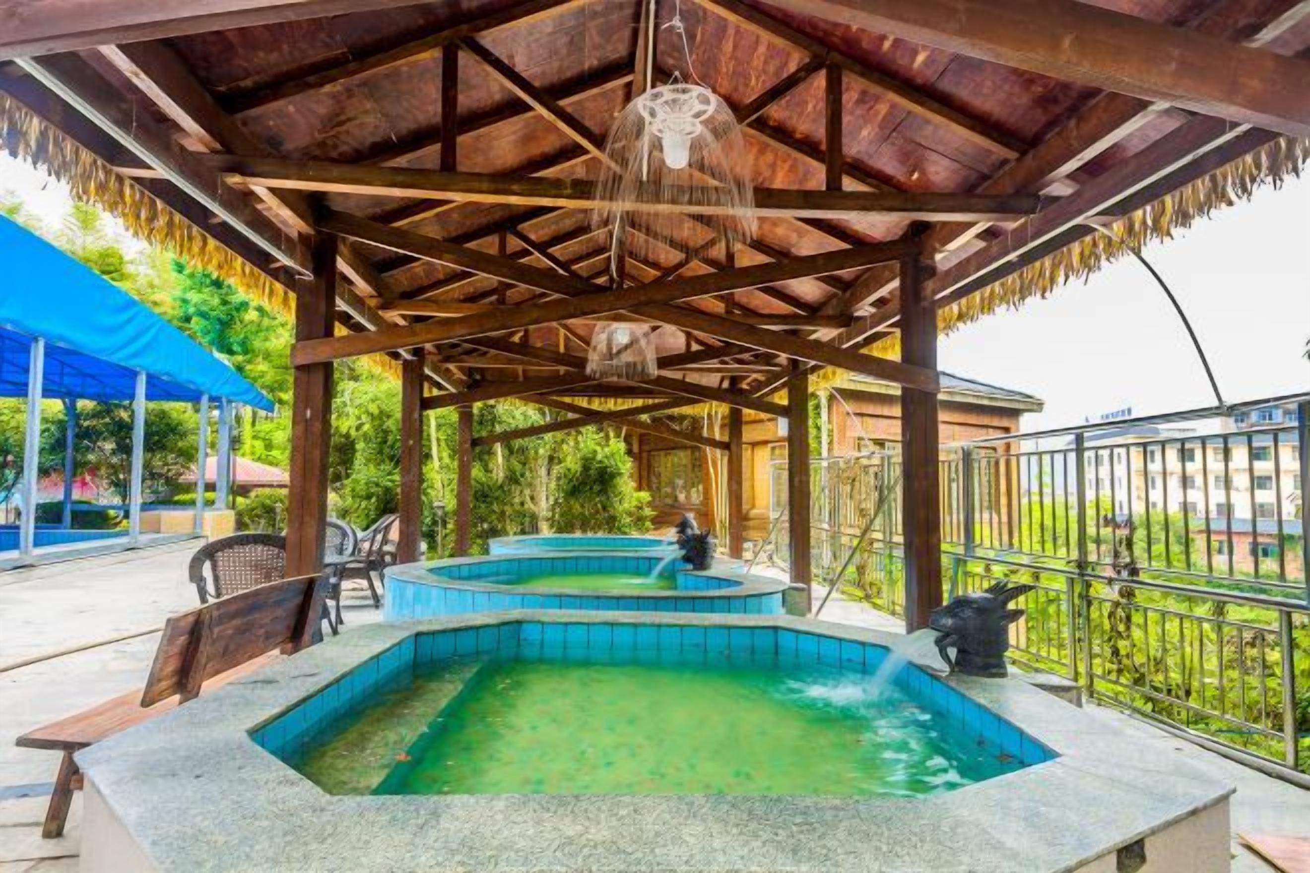 Zona de piscina exterior techada con techo de madera y baranda metálica.