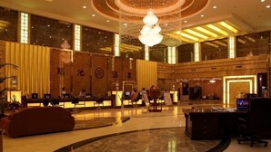 Eine geräumige Lobby mit einer Rezeption, einer Sitzecke und einer großen Kronleuchter.